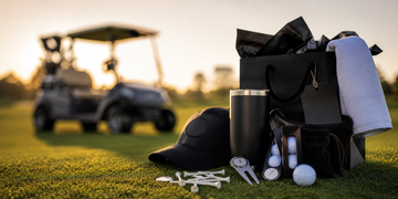 Golf tournament gift bag with practical golf accessories, tees, towel, ball markers, and Birdie Clip on grass